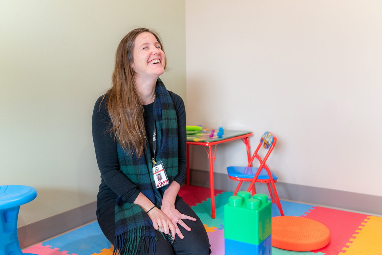 Autism assessment specialist laughs during structured play with a child, an element of an autism assessment test.