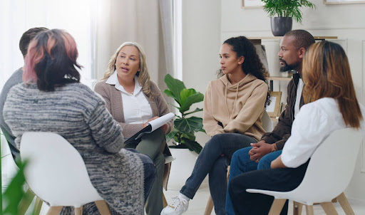 Image of a group therapy session with 2 males, 3 females, and a female therapist.