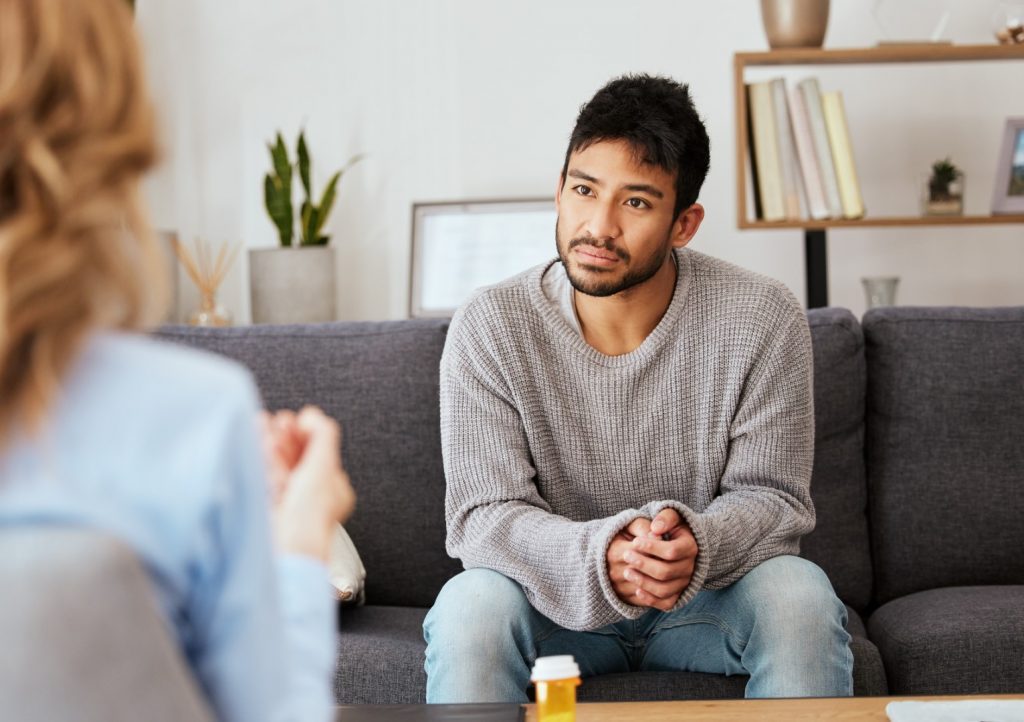 Image of a man in a counseling session with a therapist who is holding a clipboard.