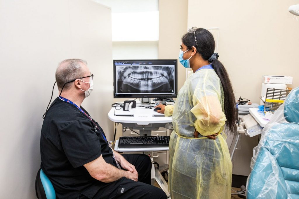 Dentist and Dental resident reviewing digital x-rays on computer screen.