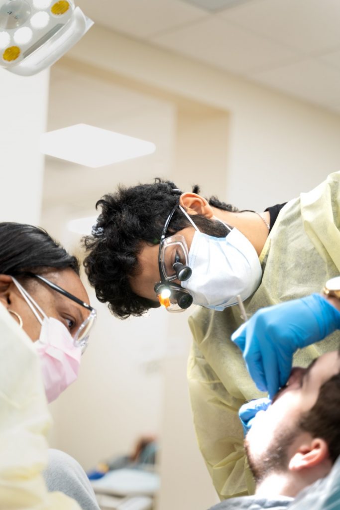 Dentist and dental assistant wearing protective gear and magnifying glasses provide dental services to a special needs patient.