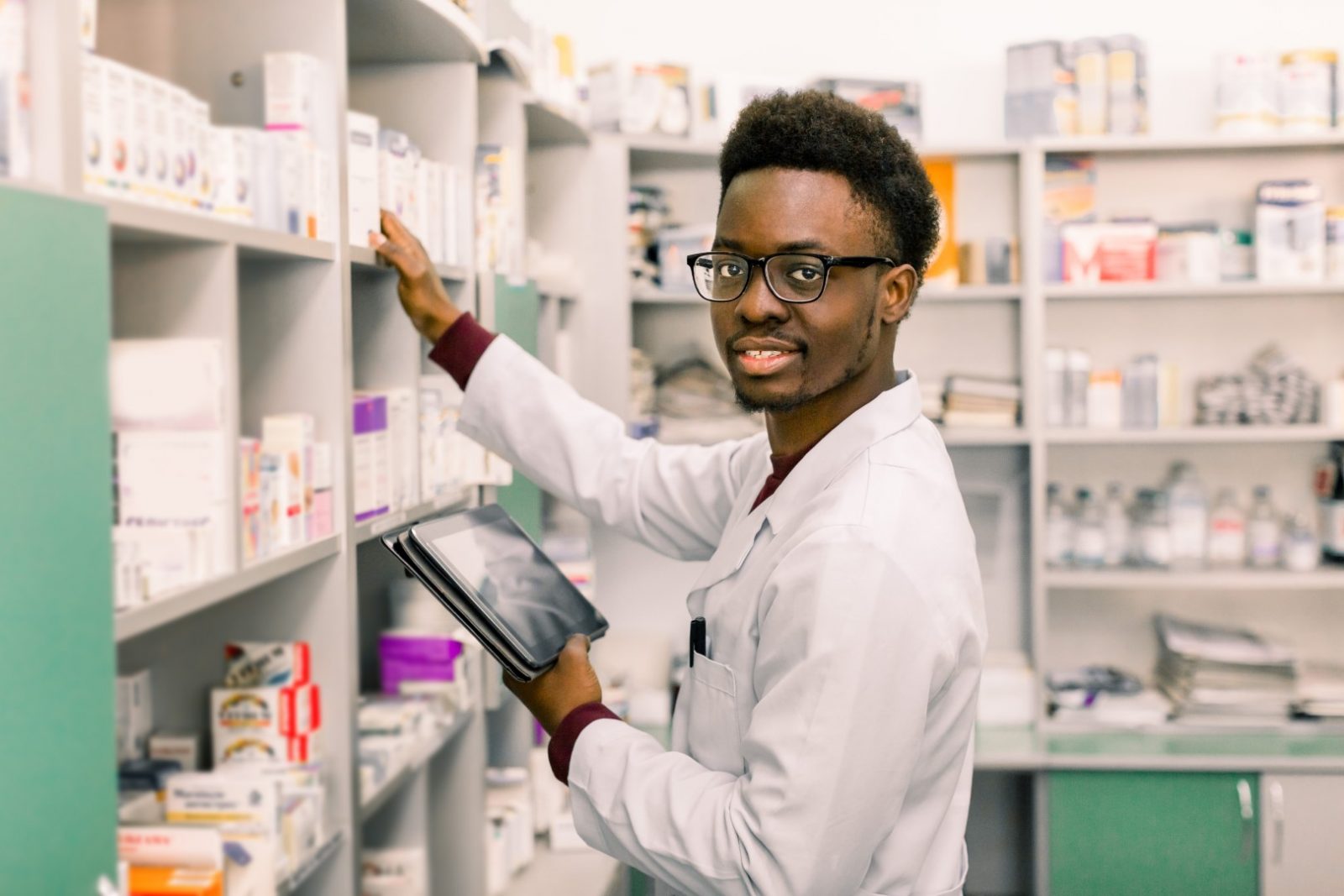 Doctor holds tablet computer and looks on pharmacy shelf for medicine used to treat disorder accompanying intellectual disability. 